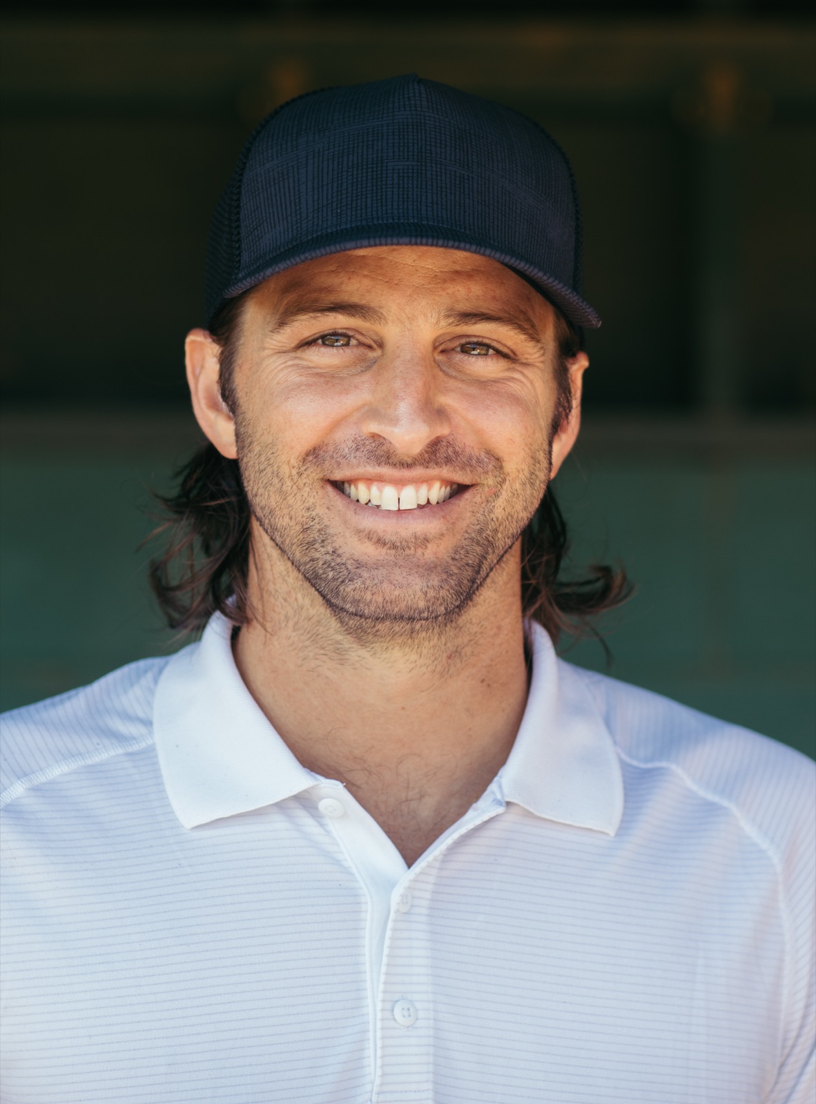 Zach Penprase in the dugout — ballcap, easy smile
